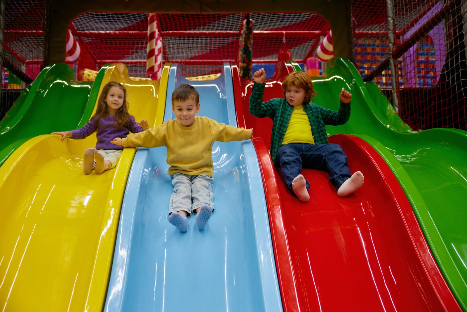 Happy children riding slide together at indoor play center