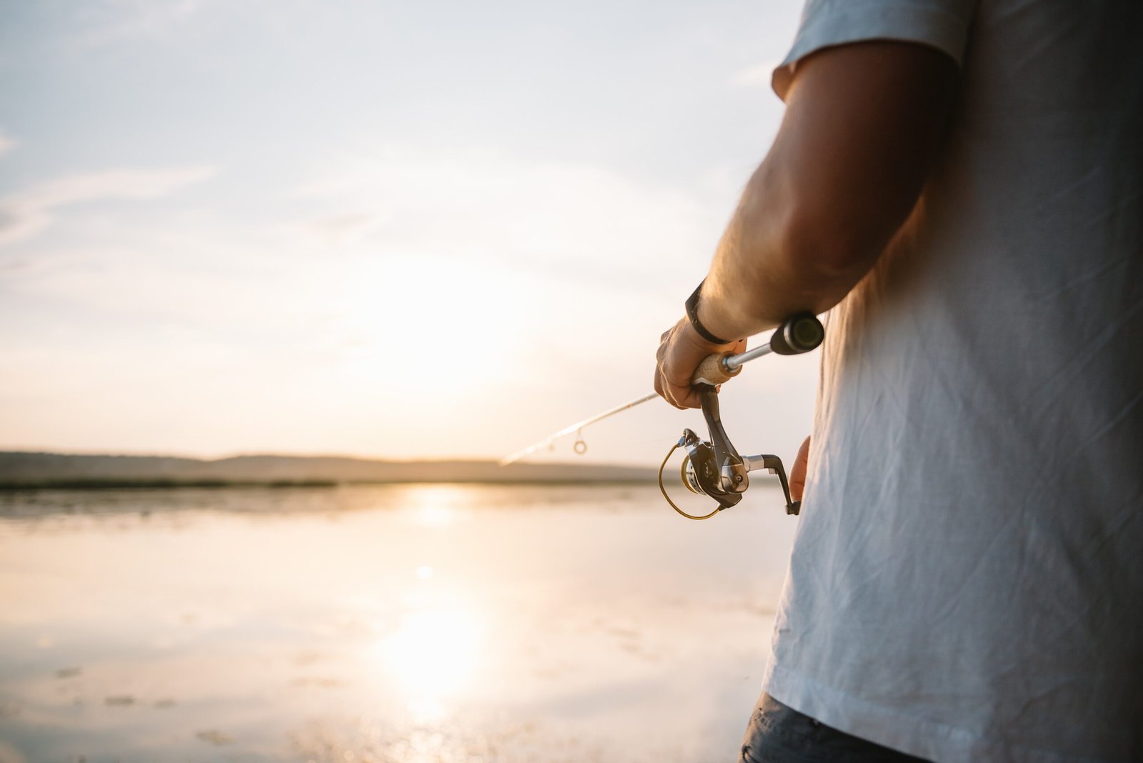 The fisherman’s hands, holds the spinning rod, rotates the coil handle. Hobby and activity.