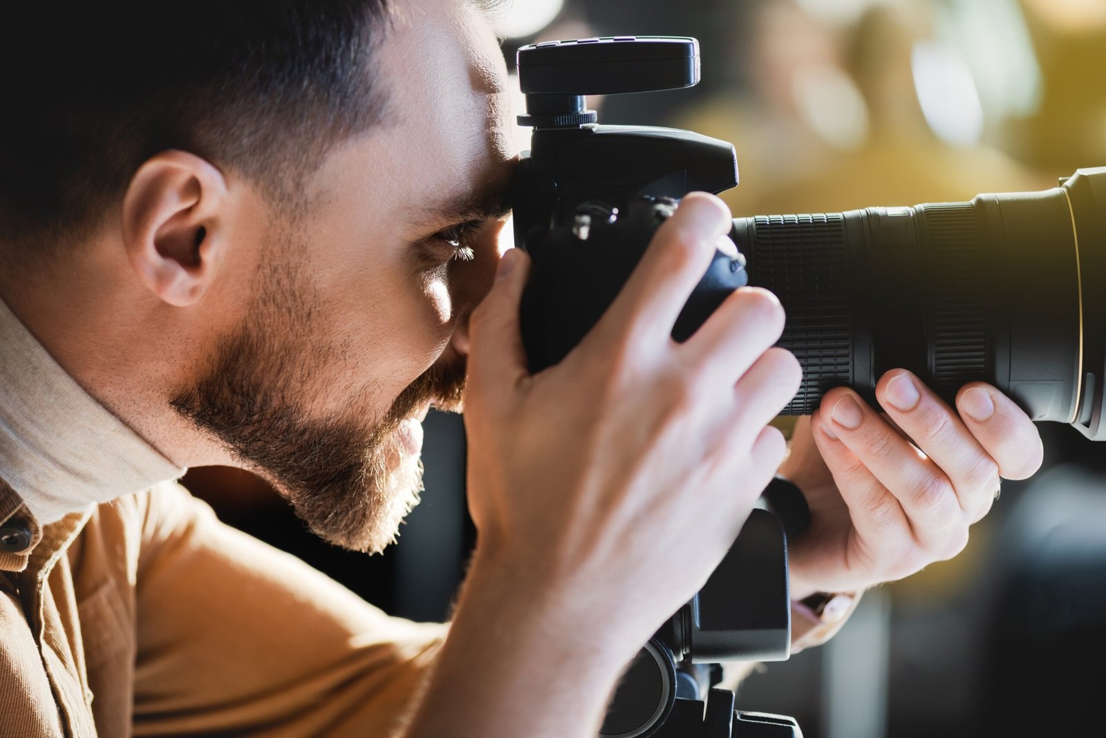side view of smiling photographer taking photo with digital camera on backstage